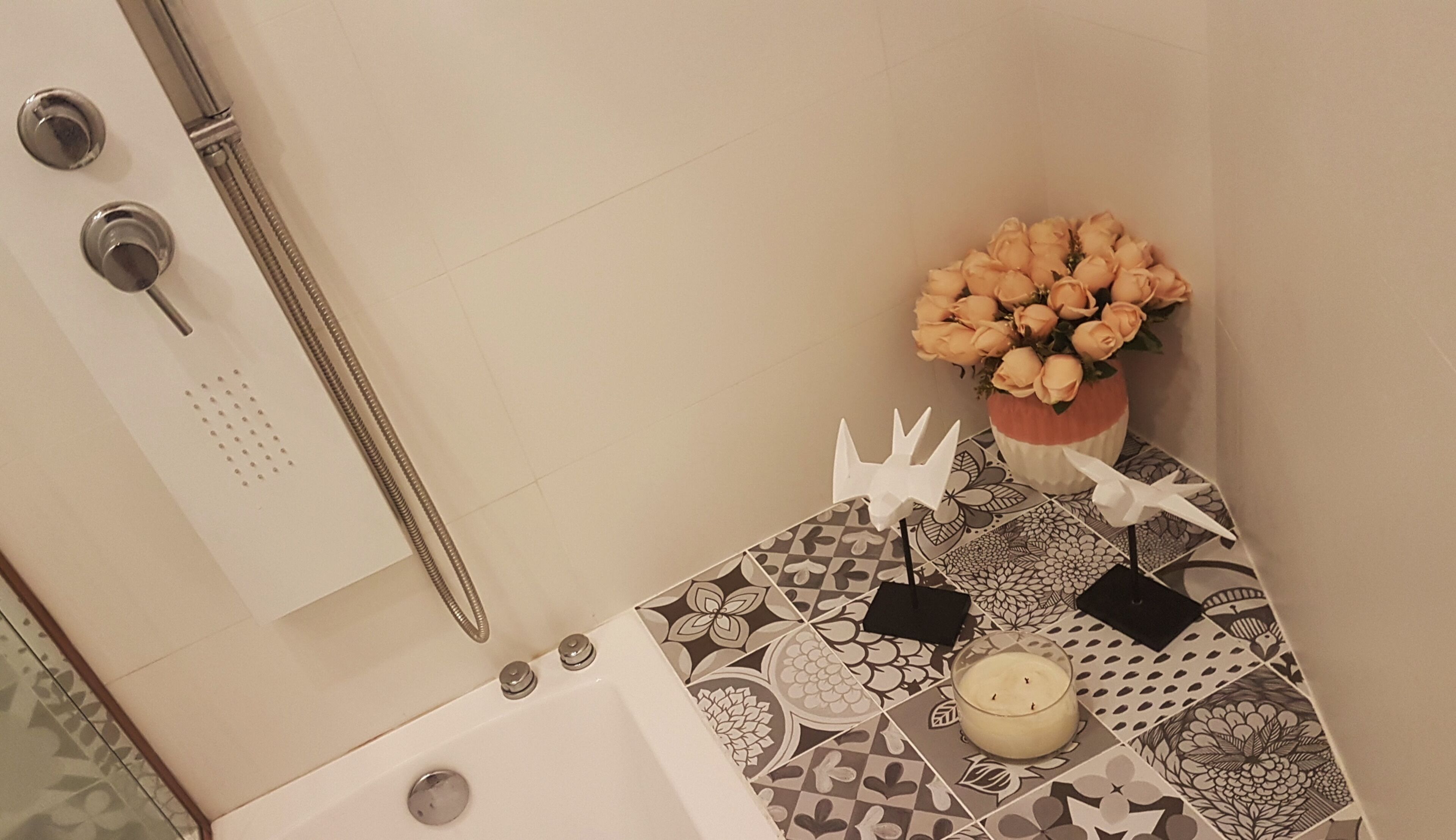 Un baño con ducha, inodoro, lavamanos, un florero y una vela.