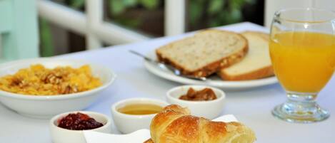 A breakfast table with croissants, toast, fruit compote, and orange juice.