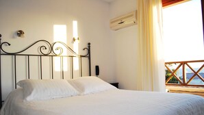 A neatly made bed with a metal headboard, a bedside table, and an air conditioning unit on the wall. - Hostal de la Barra (Punta del Este)