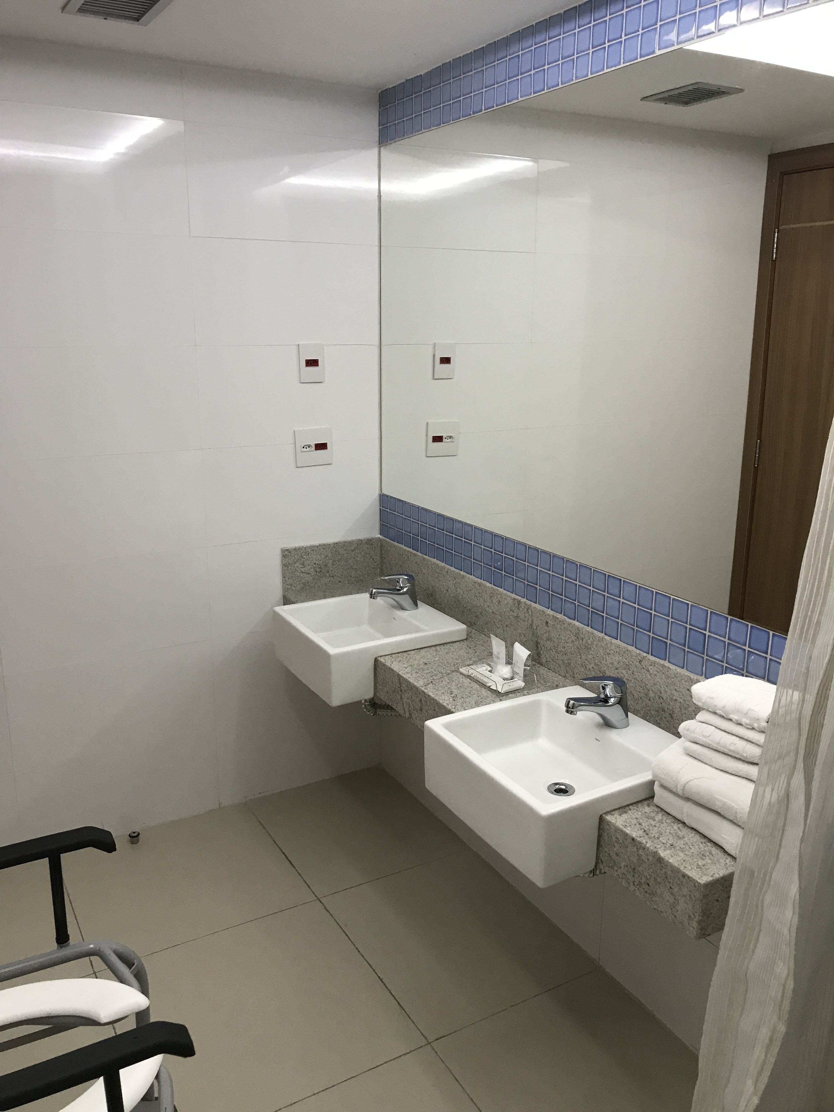 A bathroom with two sinks, a mirror, and a towel rack.