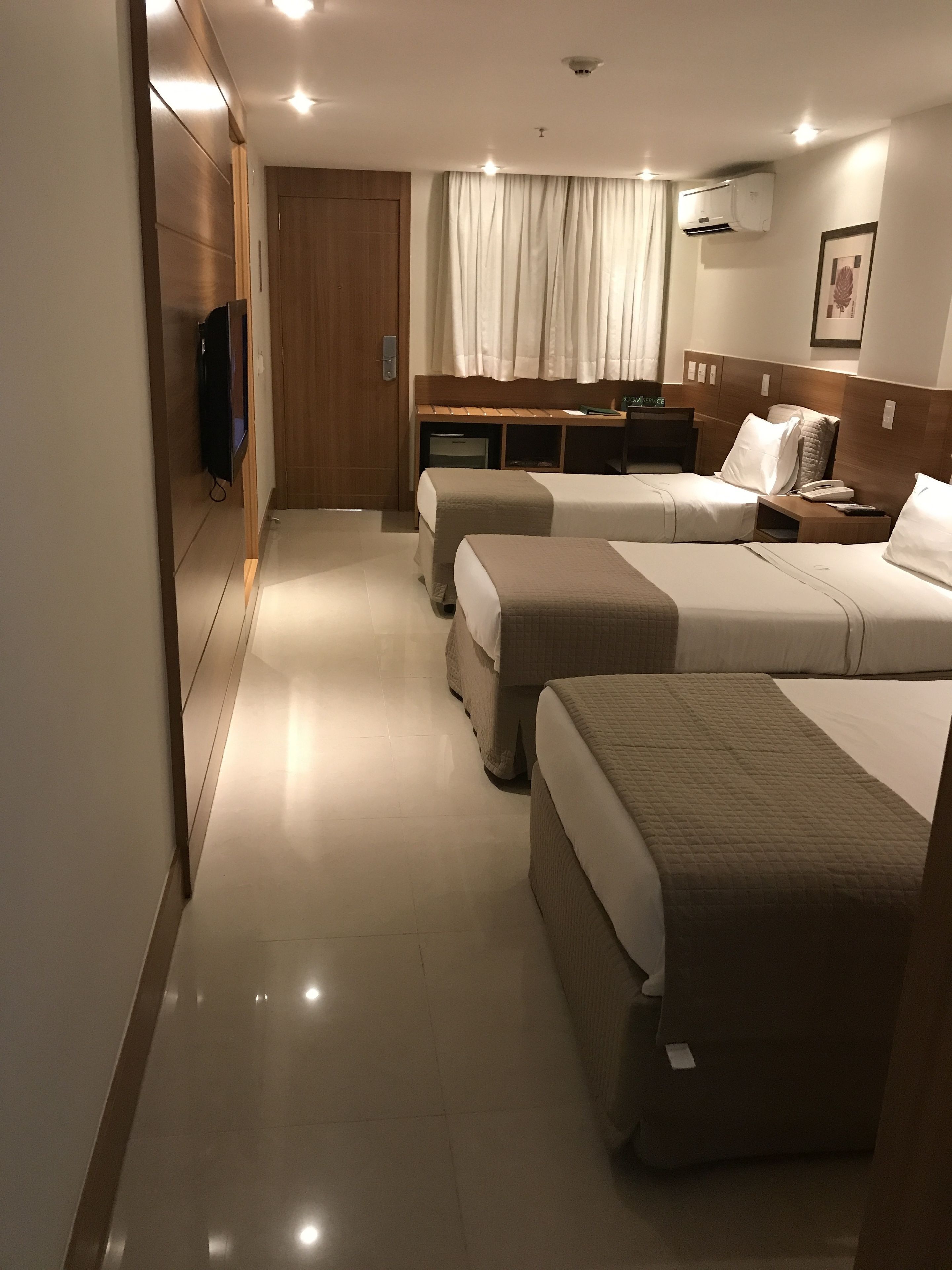Une chambre d’hôtel avec deux lits, un bureau, une télévision et un appareil de climatisation.