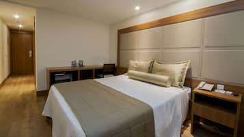 Una habitación de hotel con cama, escritorio, silla, minibar y teléfono.
