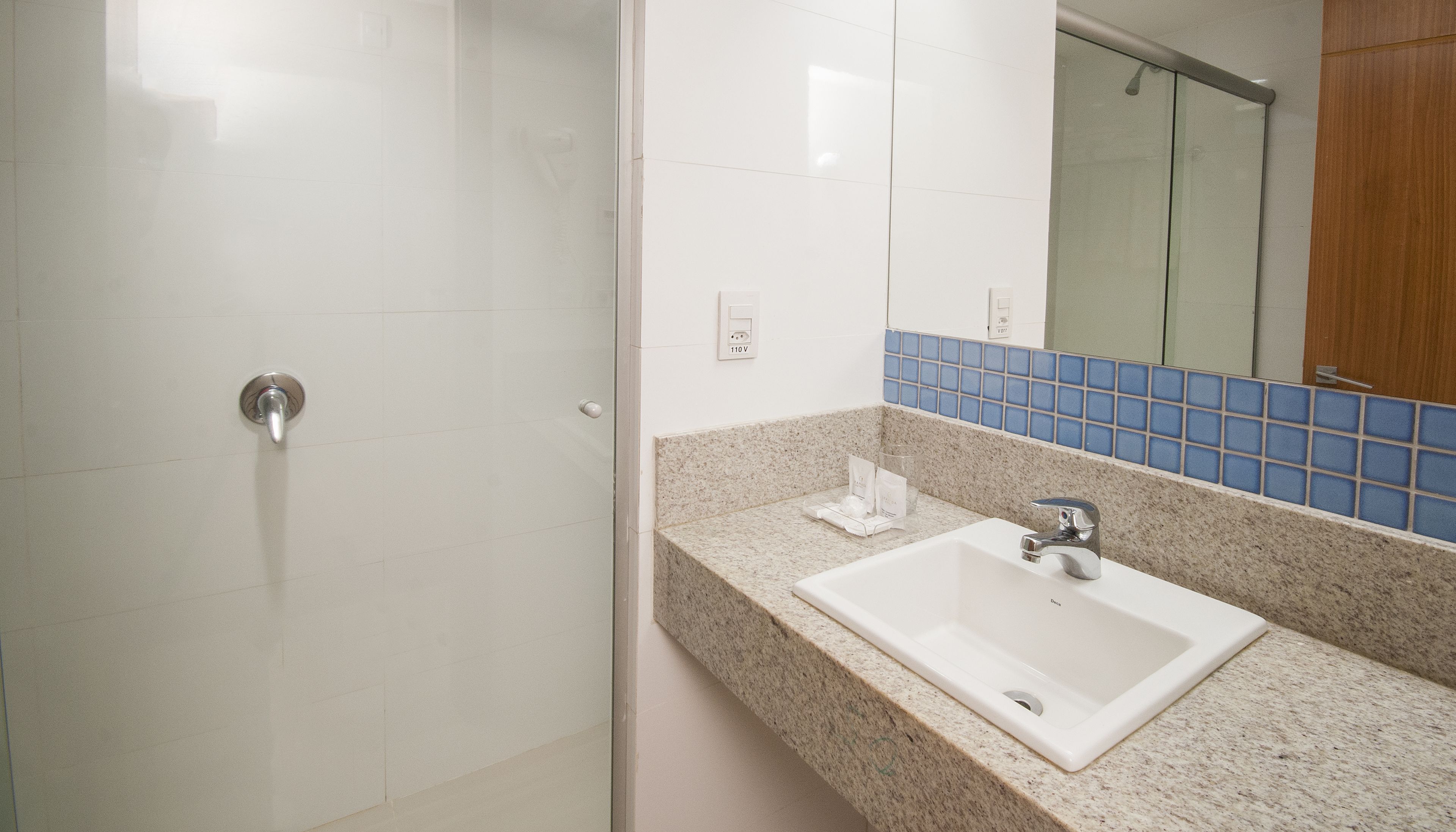 Un baño con ducha, lavabo y espejo.