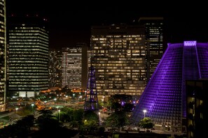 Un paisaje urbano nocturno con rascacielos iluminados y un edificio destacado con fachada púrpura.