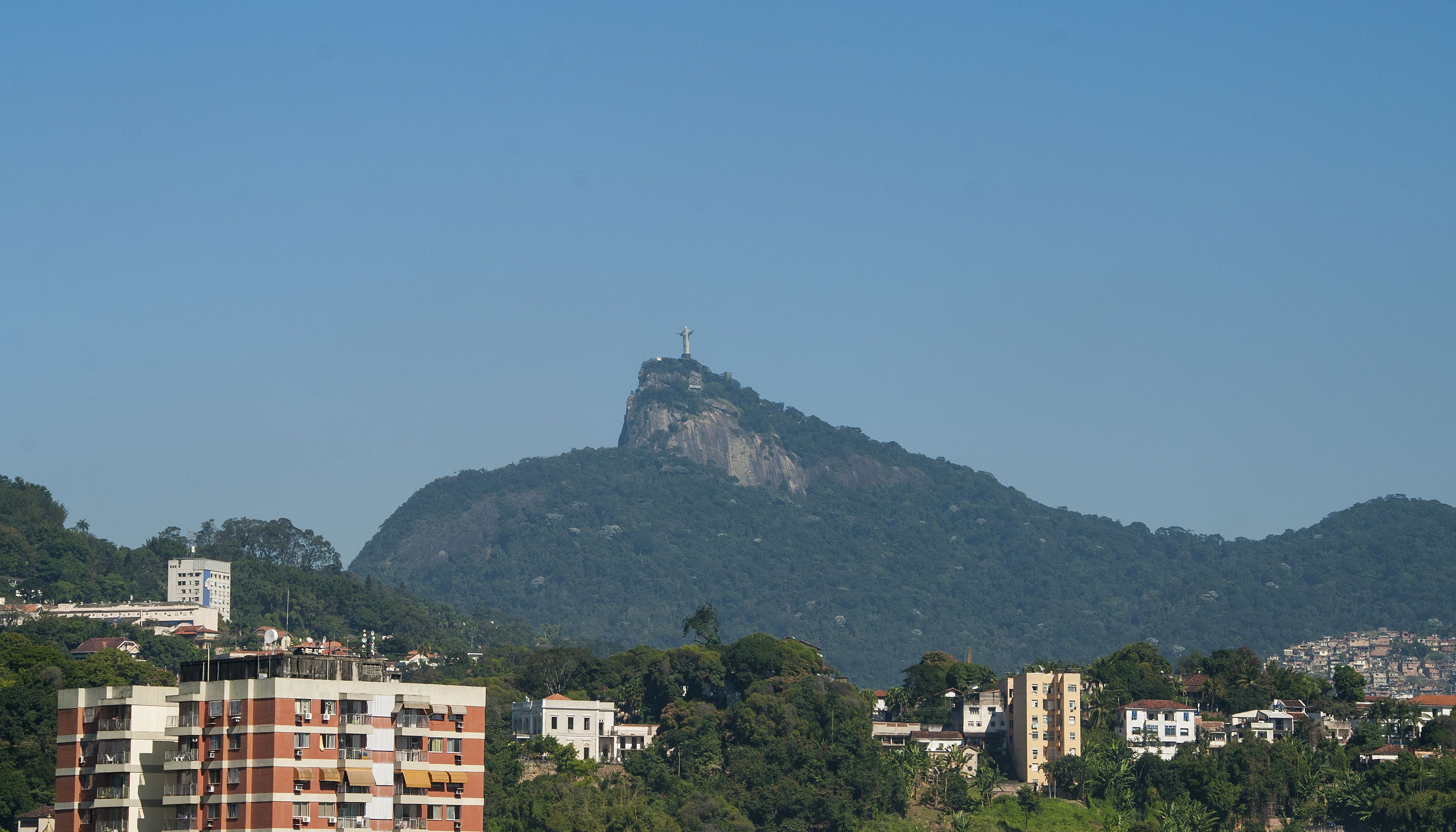 Paisagem urbana com uma montanha imponente e uma estátua no topo.