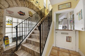 A staircase with black railings leading to a landing with a white door and a sign indicating 'CORAL HOUSE HOURS'. - The Coral House Motel (Hollywood)