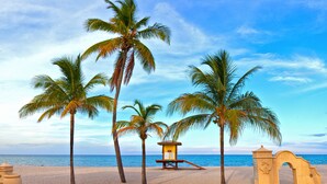 A beach with palm trees, a lifeguard tower, and a sandy walkway. - The Coral House Motel (Hollywood)