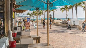 A beachside café with outdoor seating, umbrellas, and a view of the ocean. - The Coral House Motel (Hollywood)