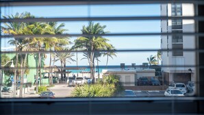 A view of a street with parked cars, palm trees, and a building with balconies overlooking the street. - The Coral House Motel (Hollywood)