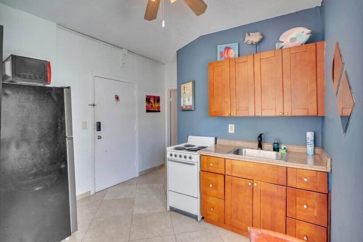 A compact kitchen with wooden cabinets, a white stove, and a refrigerator.
