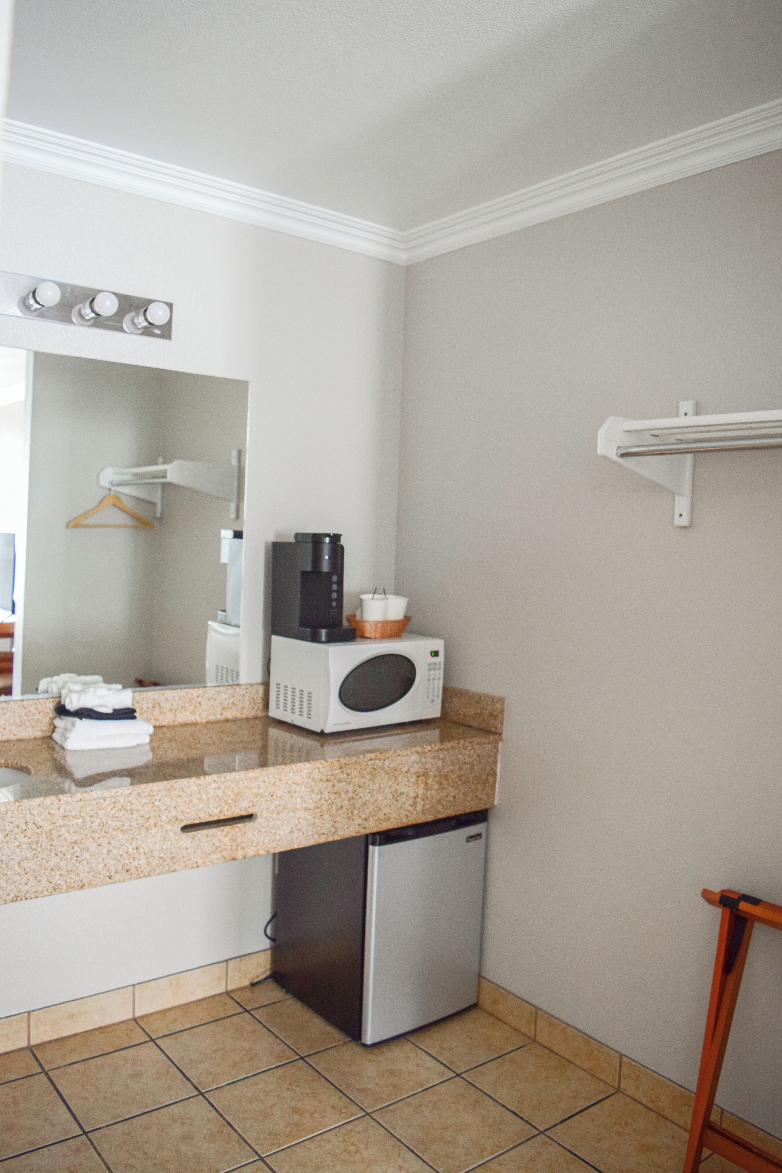 Cocina compacta con microondas, cafetera y un refrigerador pequeño.