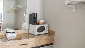 Cocina compacta con microondas, cafetera y un refrigerador pequeño.