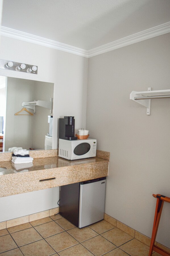 A compact kitchen with a microwave, coffee maker, and a small refrigerator.