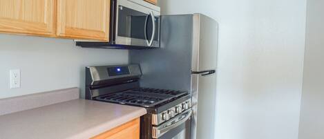 A kitchen with wooden cabinets, a stainless steel microwave, a built-in oven, and a refrigerator.