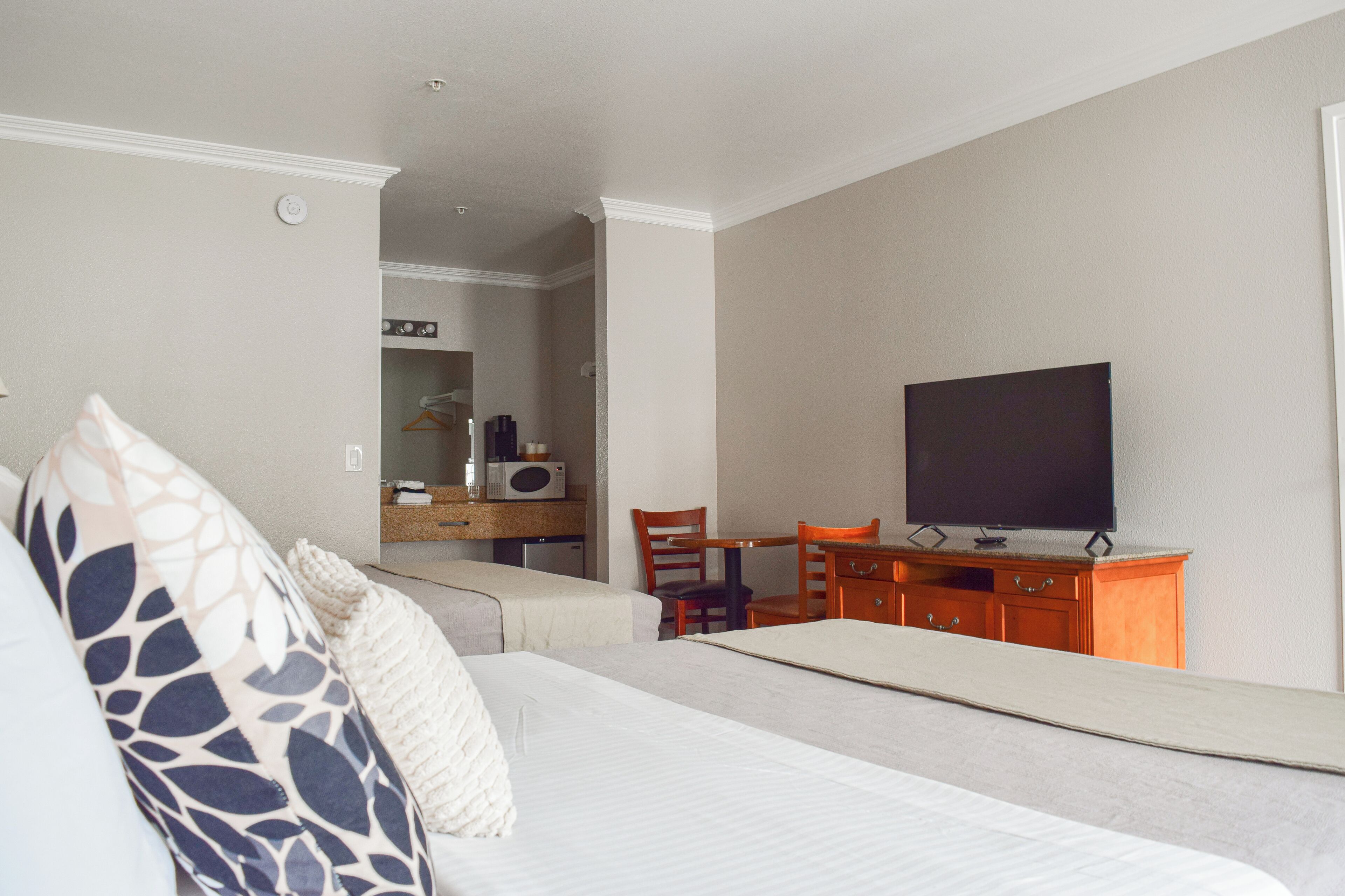 A hotel room with a bed, a desk, a television, and a mirror.