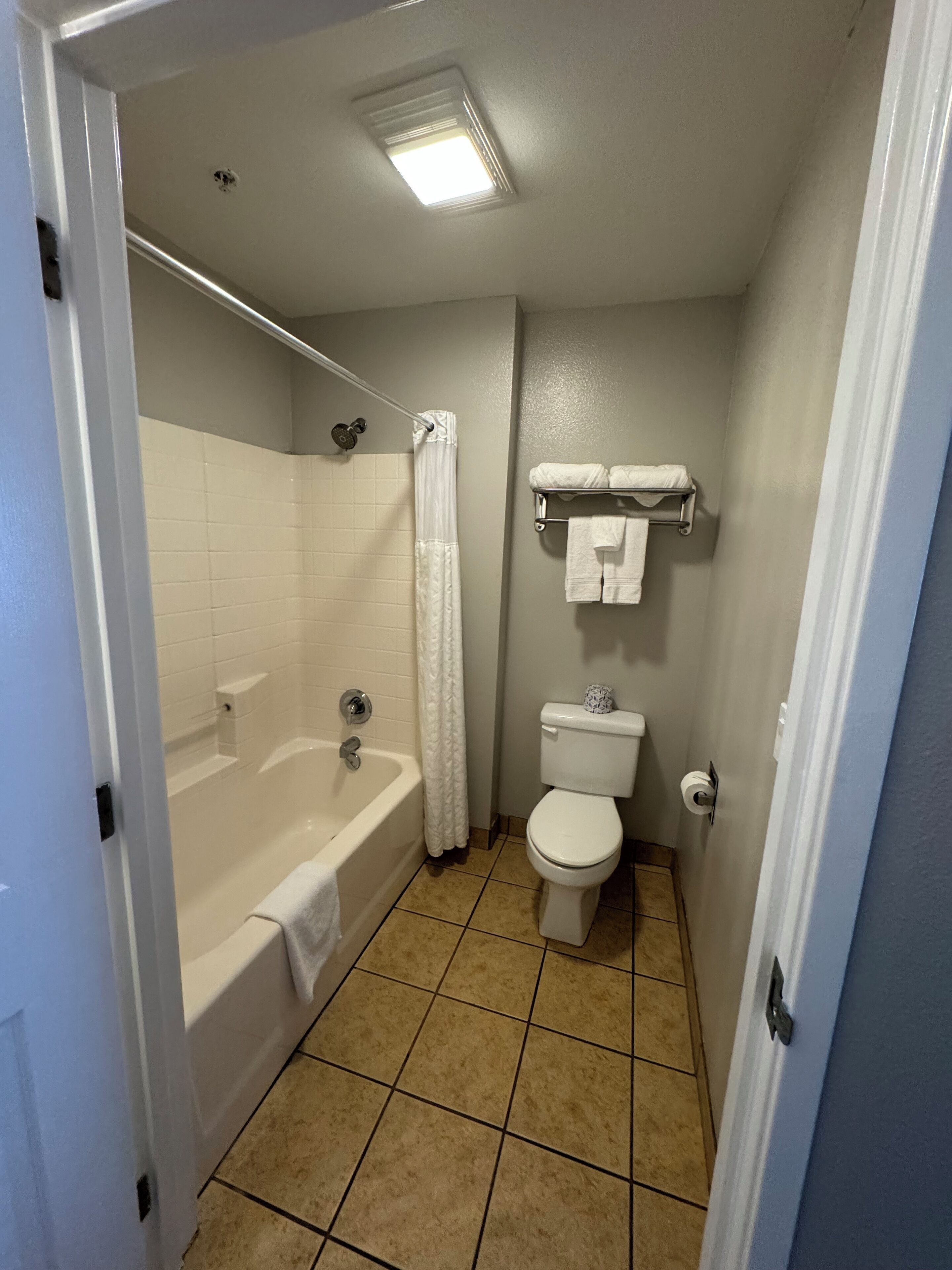 A bathroom with a bathtub, toilet, and a towel rack.
