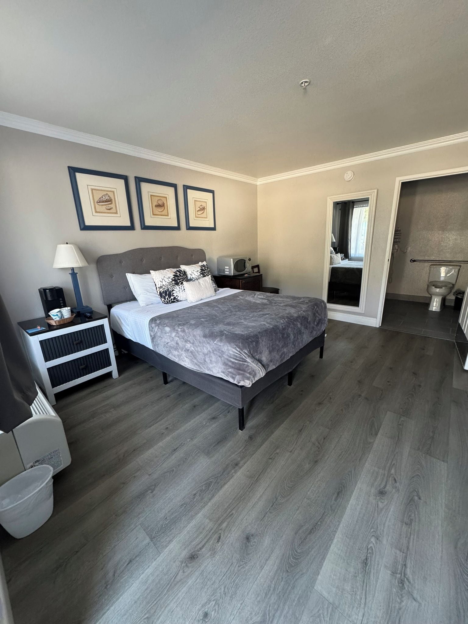 A modern bedroom with a large bed, bedside tables, a lamp, and framed artwork on the wall.