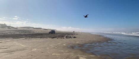 Una playa con arena, olas y cielo despejado.