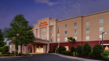 A hotel with a prominent sign, a flag, and a well-maintained entrance area.