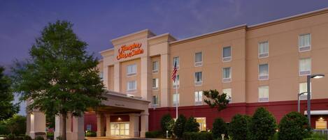 A hotel with a prominent sign, a flag, and a well-maintained entrance area.