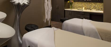 A hotel room with two beds, a bathroom with a sink and mirror, and a decorative vase on the counter.