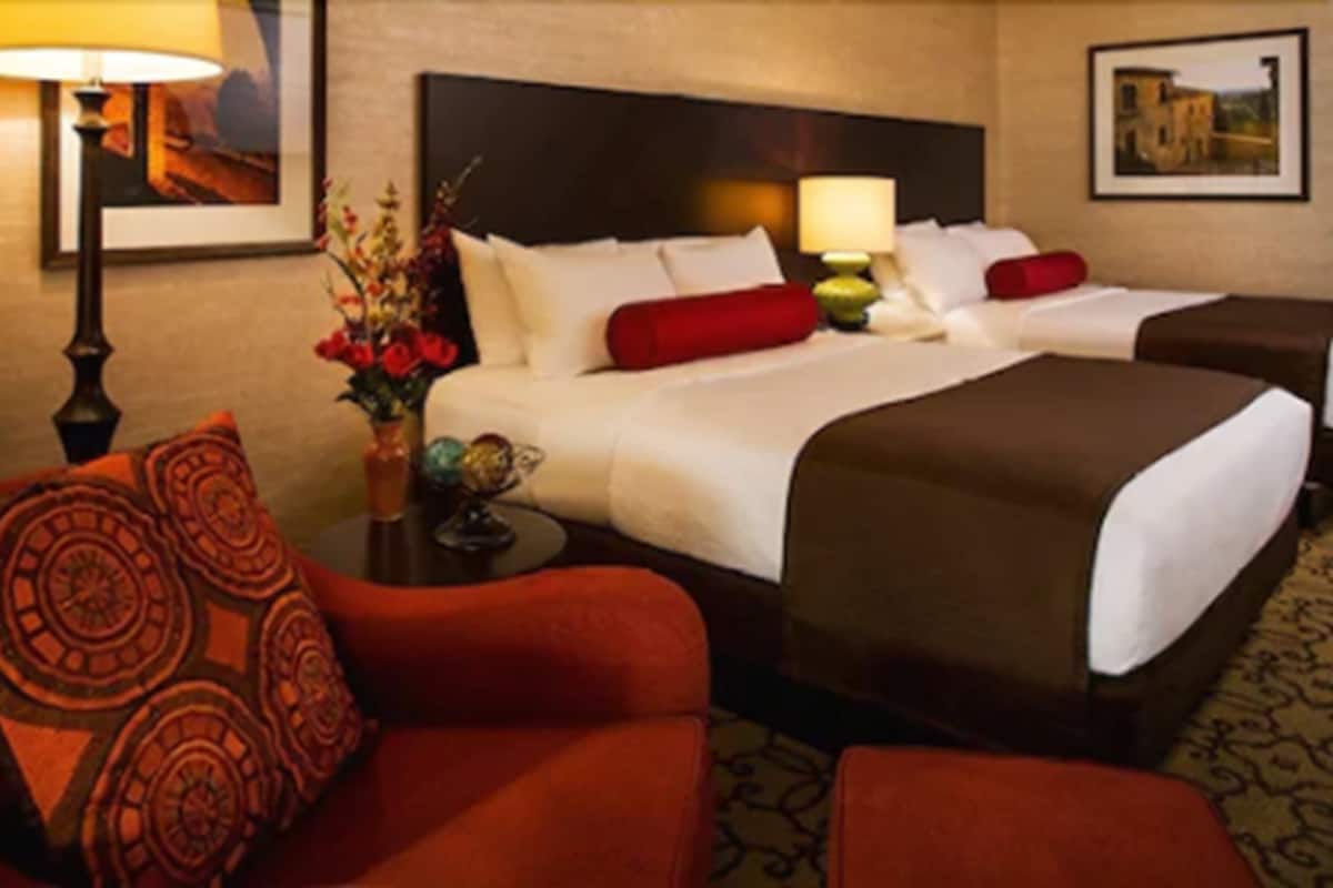 A hotel room with a bed, a sofa, a nightstand, and a lamp.
