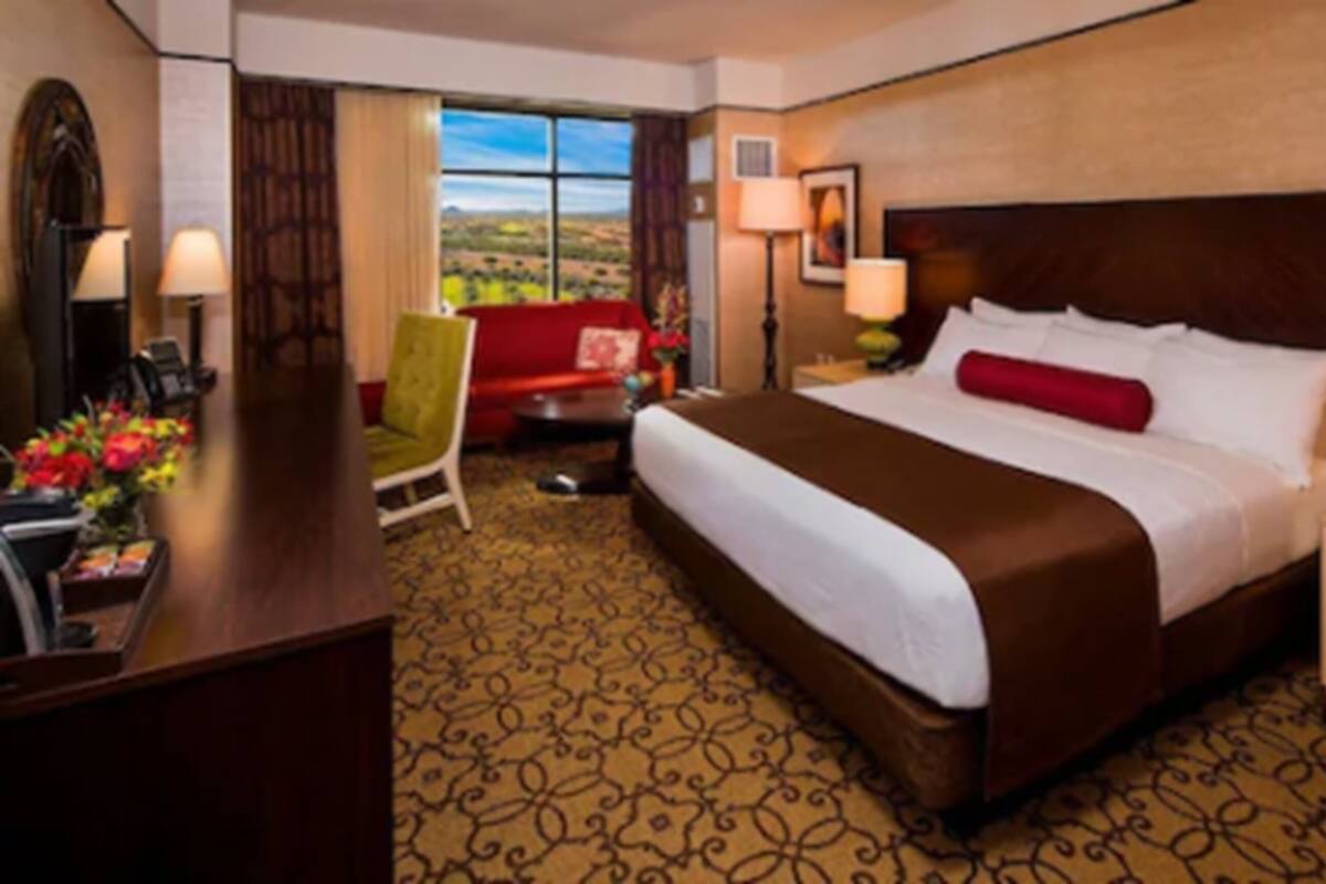 A hotel room with a large bed, a desk, a chair, and a view of the outdoors.