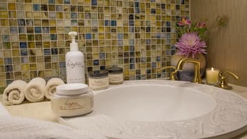 A bathroom with a white sink, a mosaic tile wall, and various toiletries.