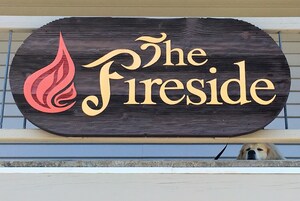 Un letrero de madera con el texto 'The Fireside' y un diseño estilizado de llama.