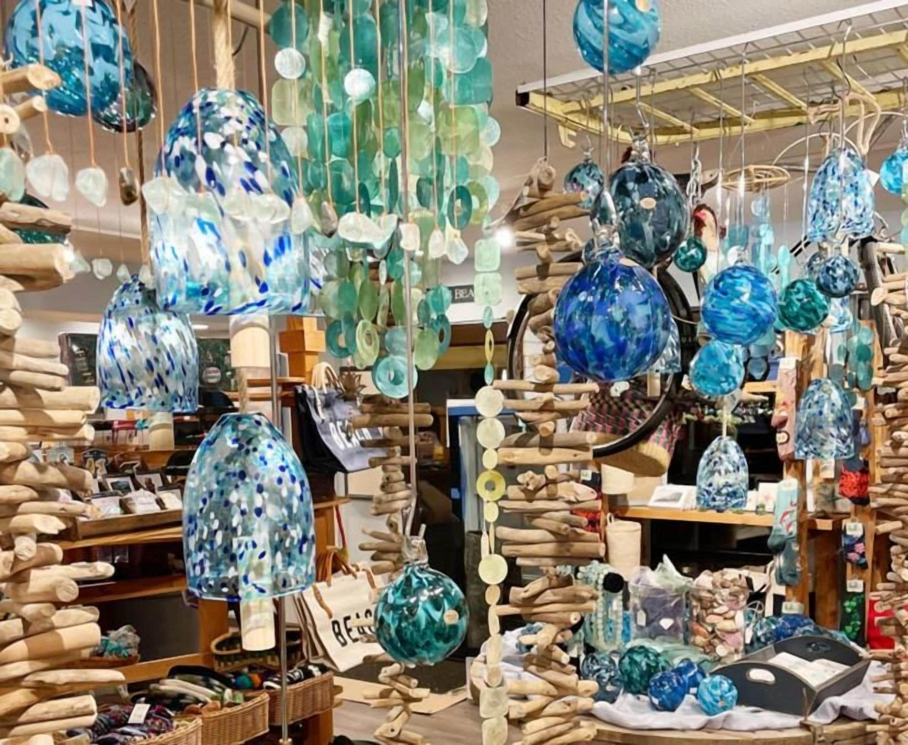 A variety of glass ornaments and decorations hanging from the ceiling in a store.