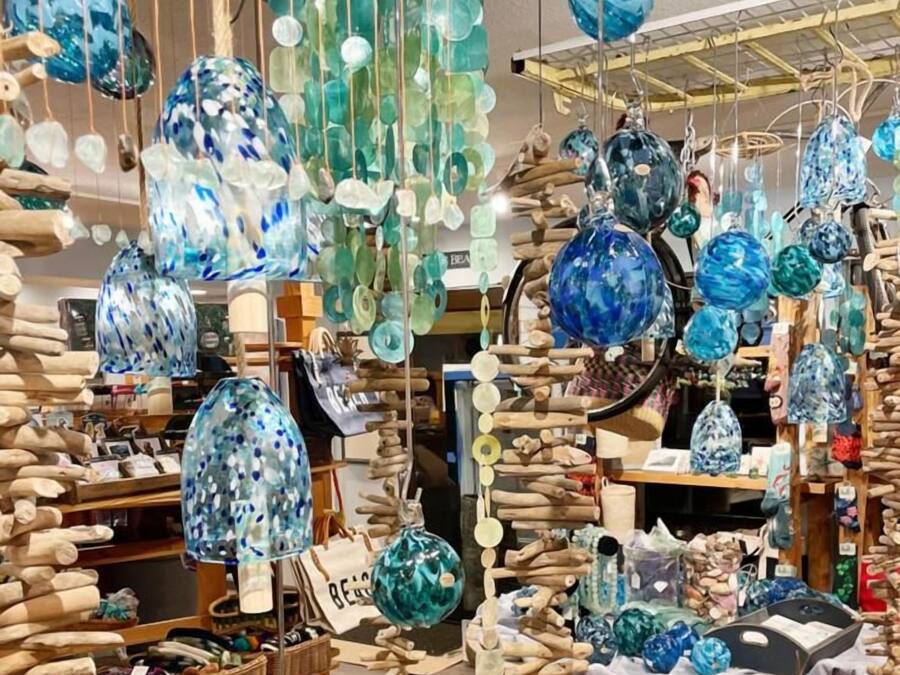 A variety of glass ornaments and decorations hanging from the ceiling in a store.