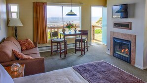 Una habitación acogedora con sofá, una mesa de comedor con sillas, chimenea y televisor montado en la pared.