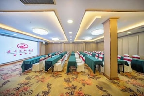 A conference room with rows of tables and chairs, a projector screen, and a carpeted floor. - Urumqi Oriental Dynasty Hotel (People's Cinema · Xiaoximen Branch) (Urumqi)