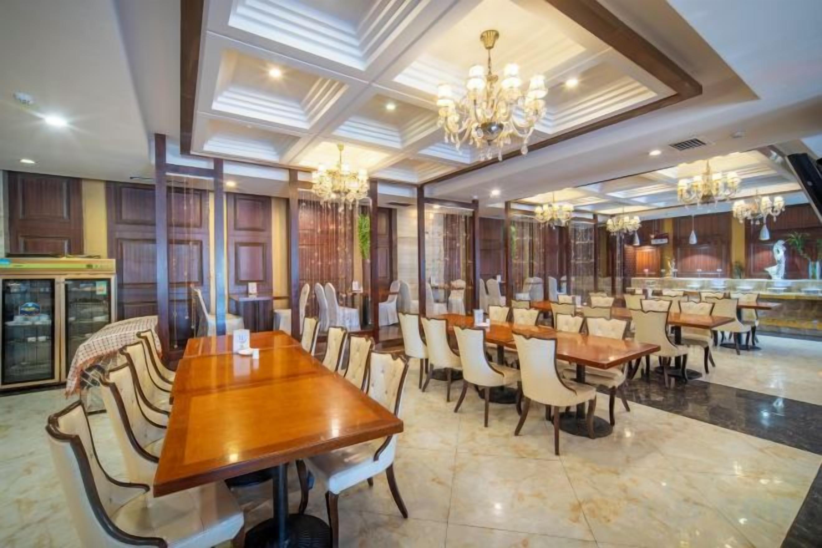 A spacious dining area with multiple tables and chairs, chandeliers, and a modern interior design.