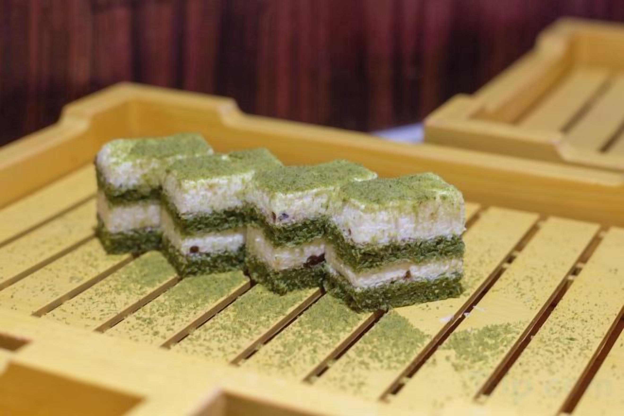 A tray with rectangular food items, possibly sushi, on a yellow surface.