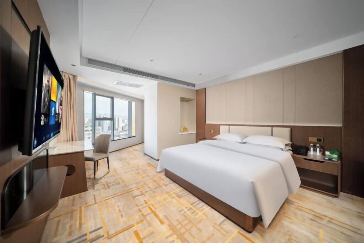 A hotel room with a bed, a TV, a desk, and a chair.