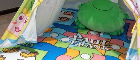 A tent with a cartoon character plush toy inside, placed on a colorful mat with 'PAUL FRANK' text.