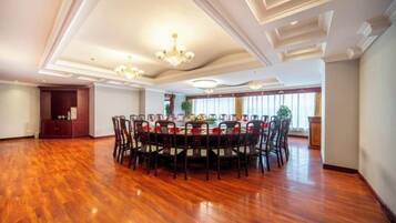 A spacious dining area with a round table surrounded by chairs, a chandelier, and a view of the outdoors.