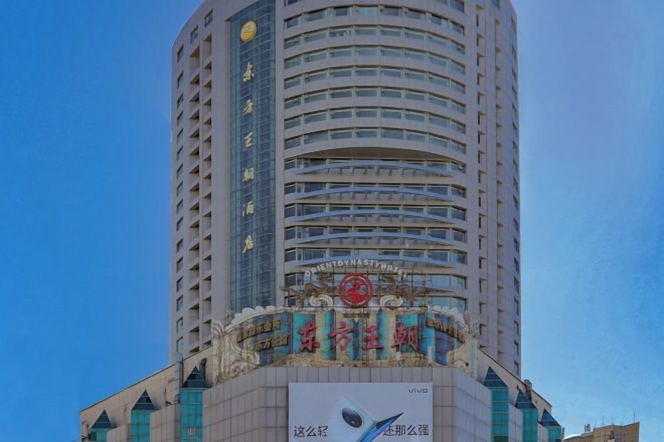 A tall hotel with a prominent sign at the top and a large advertisement at the base.