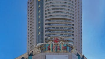 A tall hotel with a prominent sign at the top and a large advertisement at the base.