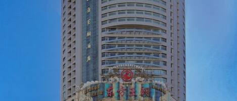 A tall hotel with a prominent sign at the top and a large advertisement at the base.