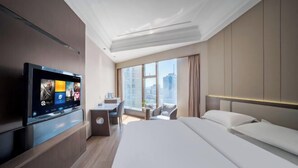 Ein modernes Hotelzimmer mit einem großen Bett, einem Schreibtisch, einem Flachbildfernseher und Blick auf die Stadt.