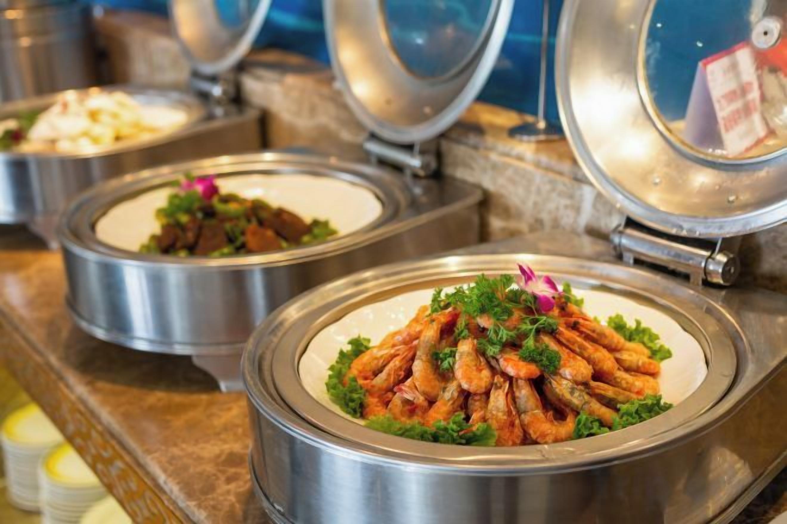 A buffet with various dishes, including a shrimp dish garnished with parsley.
