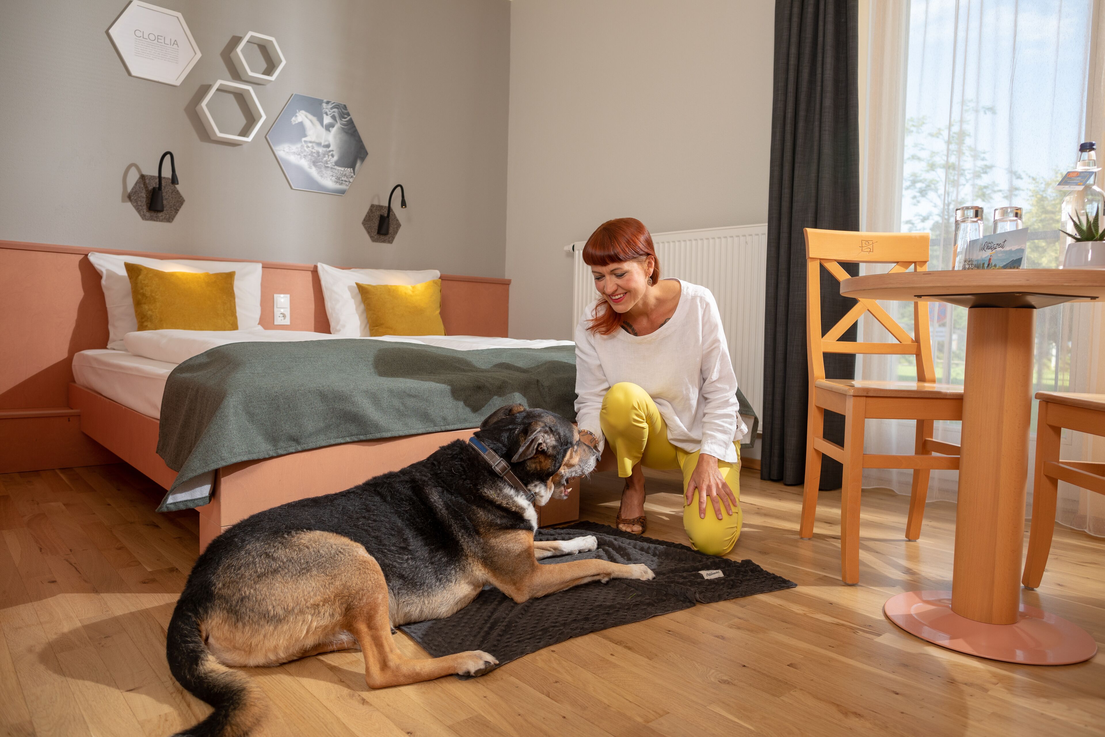 Ein Schlafzimmer mit einem Bett, einem Hund, einem Tisch und einem Stuhl.