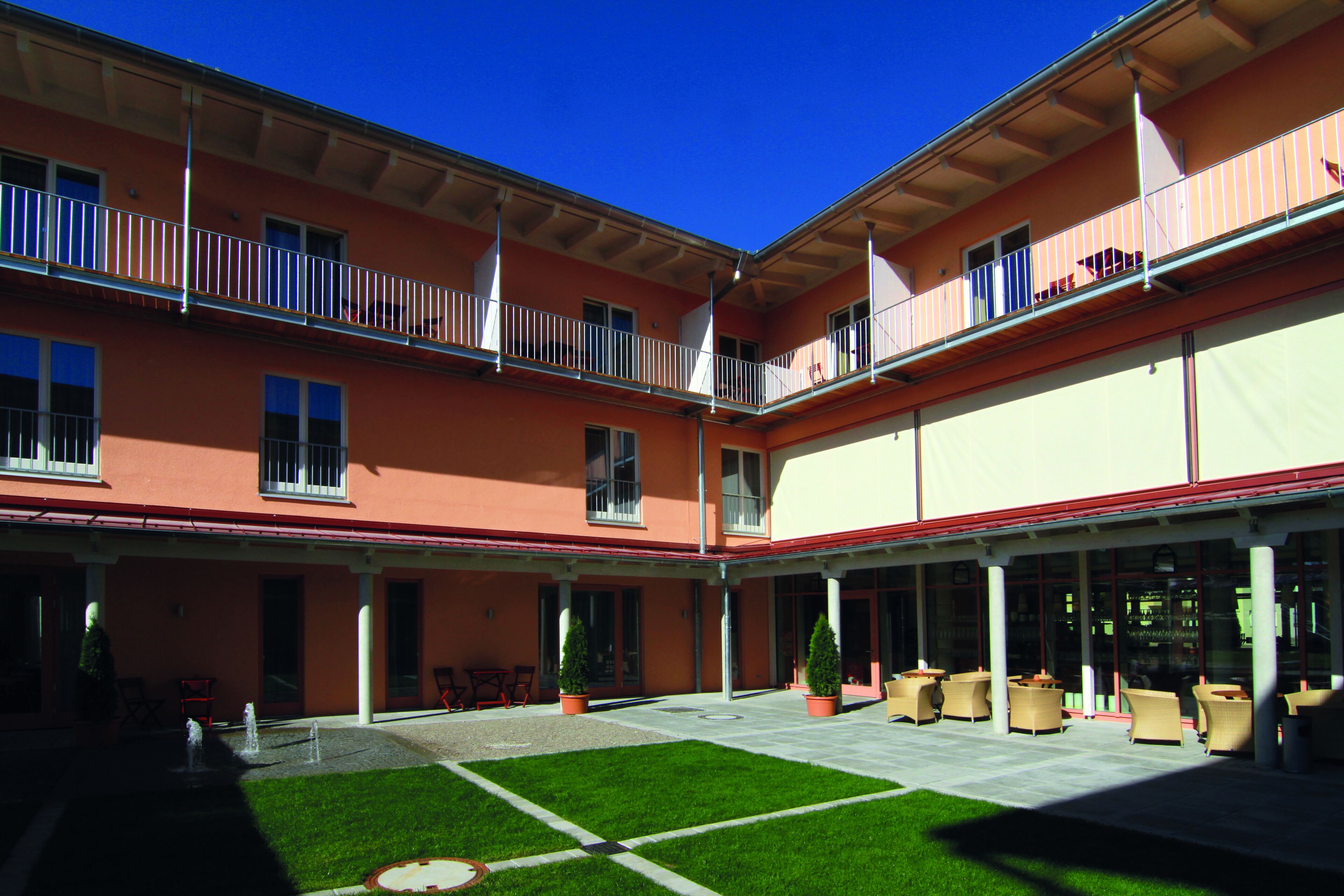 A courtyard with outdoor seating, a lawn, and a building with balconies.