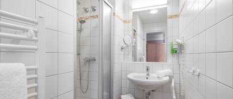 Une salle de bain avec une douche, un lavabo et un porte-serviettes.