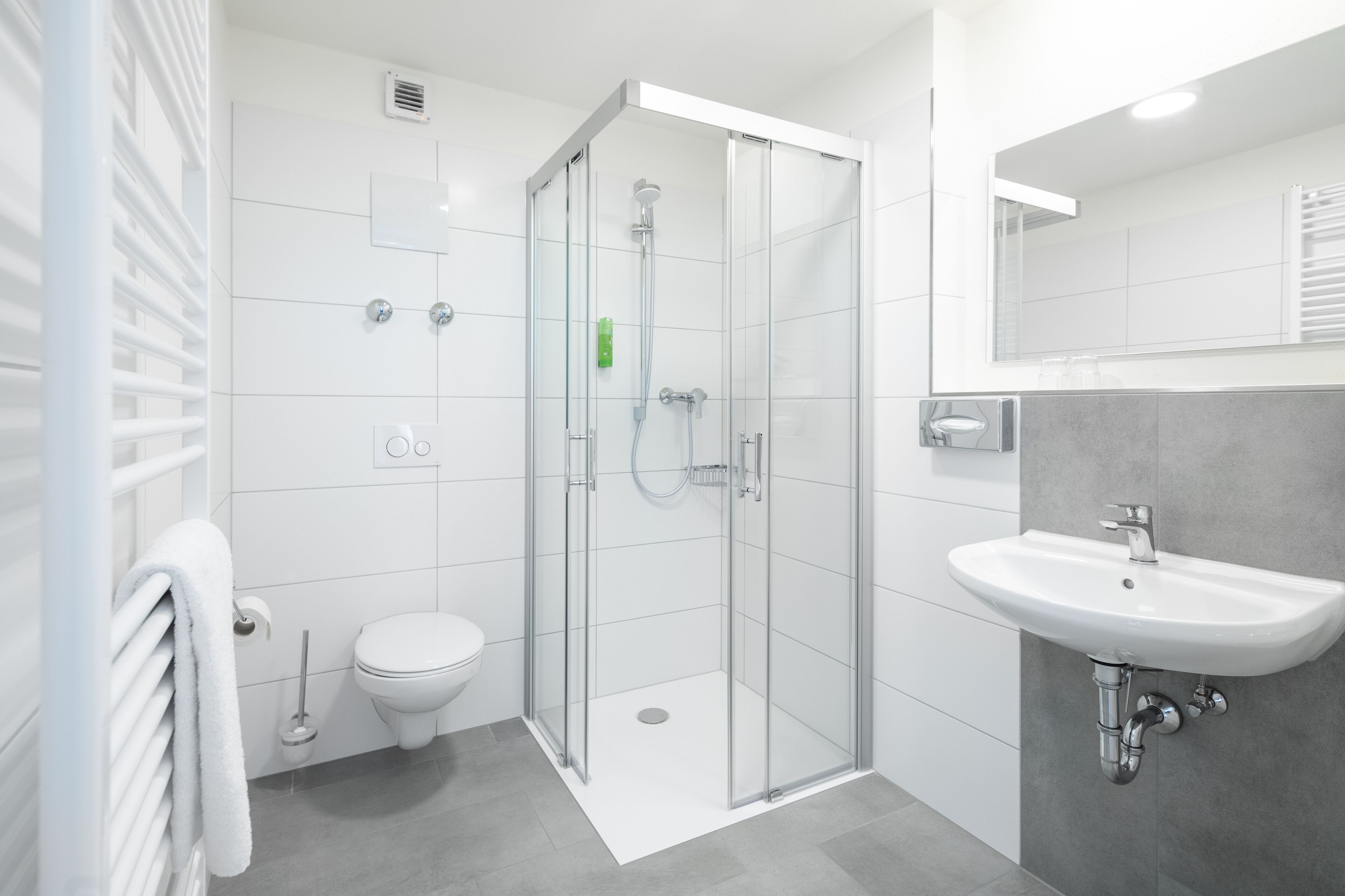 A modern bathroom with a glass-enclosed shower, a white toilet, and a wall-mounted sink.