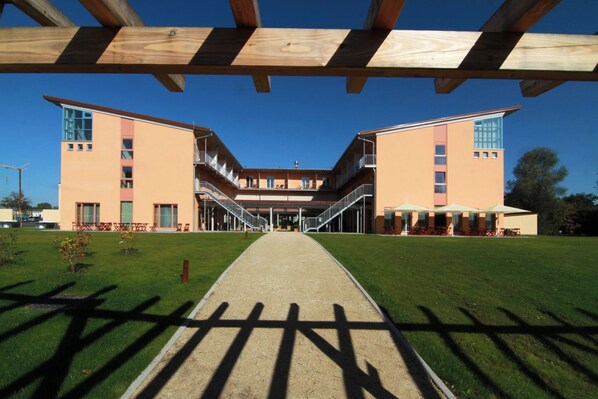 A modern building with a central courtyard, featuring a covered walkway and outdoor seating area. - JUFA Hotel Kempten (Kempten)