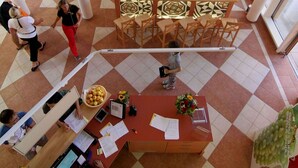 Un vestíbulo espacioso con suelo a cuadros, una recepción y una zona de estar con mesas y sillas.