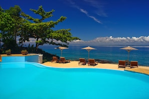 Una piscina al aire libre, sombrillas, sillones reclinables de piscina